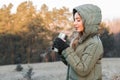 Cold in the mountains. woman tourist outdoor at sunrise holding a thermos with tea or coffee and getting warm