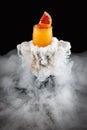 Cold orange lemonade surrounded by smoke on a dark background