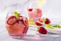Cold pink strawberry flavoured jin and tonic garnished with fresh fruits and mint leaves