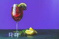 Cold red cocktail in tall glass on violet background