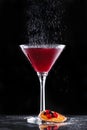 Cold red cocktail with red currant and powdered sugar in tall glass on black background. Summer drinks and alcoholic cocktails