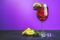 Cold red cocktail in tall glass on violet background