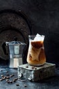 Cold refreshing iced coffee with cream in a tall glass and coffee beans on dark background. Royalty Free Stock Photo