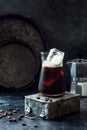 Cold refreshing iced coffee in a tall glass and coffee beans on dark background. Royalty Free Stock Photo