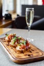 Platter: cold salmon bruschetta and greens with a glass of champagne