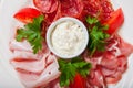 Cold smoked meat plate with prosciutto, salami, bacon, ham and sauce on a white plate. Royalty Free Stock Photo