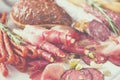 Cold smoked meat plate. Traditional italian antipasto, cutting board with salami, prosciutto, ham, pork chops, olives on grey Royalty Free Stock Photo