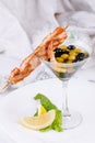 Cold snack from shrimps and fish shish kebab with original serving of olives in an elegant glass. Royalty Free Stock Photo