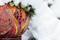 Cold snow day with close-up of gold, red, yellow, orange, bright multicolored stained glass mosaic garden art ball in winter