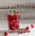 Cold sparkling hibiscus or karkade tea with lemon, mint, and ice in glass on a wooden table. Royalty Free Stock Photo