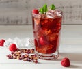 Cold sparkling hibiscus or karkade tea with lemon, mint, and ice in glass on a wooden table. Royalty Free Stock Photo