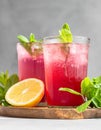 Cold sparkling hibiscus or karkade tea with lemon, mint and ice in glasses on a grey stone background. Summer drink, lemonade Royalty Free Stock Photo