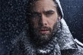 That cold stare could melt any heart. a serious young man covered in snow in the dark. Royalty Free Stock Photo