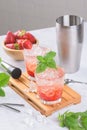 Cold strawberry cocktail mojito, margarita, daiquiri in two glasses with mint, ice and bartender tools on light table Royalty Free Stock Photo