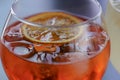 Cold summer alcohol cocktail with ice and orange in a wine glass and black plastic straw on light blurred background Royalty Free Stock Photo