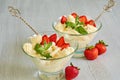 Cold summer dessert with sliced strawberries, cheese cream in the glass bowls on the gray kitchen table decorated with fresh mint Royalty Free Stock Photo