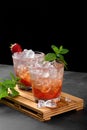 Cold summer strawberry iced cocktail mojito, margarita, daiquiri in two glasses with mint leaves on dark background Royalty Free Stock Photo