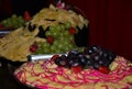 A cold table with plates full of different types of cheese, purple grapes and green grapes, strawberries and other fruits Royalty Free Stock Photo