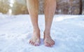 Cold training and acclimation concept. Senior guy standing barefoot on snow at winter forest, cropped view Royalty Free Stock Photo
