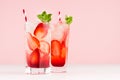 Cold tropical strawberry juices in misted glass with sliced berries, mint, ice cubes, straw on pastel pink background. Royalty Free Stock Photo