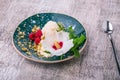 Cold vanilla ice cream with decorative flower and mint on a wooden background. A dessert with raspberries and nuts.