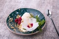 Cold vanilla ice cream with decorative flower and mint on a wooden background. A dessert with raspberries and nuts.