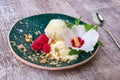 Cold vanilla ice cream with decorative flower and mint on a wooden background. A dessert with raspberries and nuts.