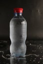 Cold water in a bottle on a black background. A bottle of water stands on a black background. Cool summer drinks Royalty Free Stock Photo