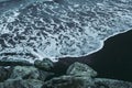 Cold waters of Atlantic Ocean on black sand beach in Iceland. View from gray rocks Royalty Free Stock Photo