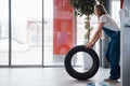 Cold weather outside. Woman walks with brand new wheel to the car. Conception of repair Royalty Free Stock Photo