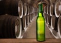 cold wet beer bottle in the cellar with vintage kegs Royalty Free Stock Photo