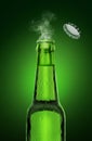 Cold wet open beer bottle with smoke on green background Royalty Free Stock Photo