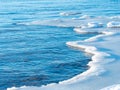 Cold winter sea shore at sunset. Tree silhouettes in the foreground Ice pieces on the sea shore. Royalty Free Stock Photo