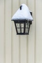 Cold winter, snow and ice covered black light fixture on an exterior wall Royalty Free Stock Photo