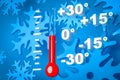 Cold winter weather concept. Thermometer measuring air temperature isolated blue snowflakes background