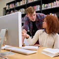 Collaborating on an assignment. two students working together at a computer in a university library. Royalty Free Stock Photo