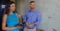 Collaborating colleagues analyzing financial charts on whiteboard at office, with tablet and marker Royalty Free Stock Photo