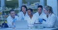 Collaborating scientists analyzing data on laptop at research lab bench, with pipette and flasks Royalty Free Stock Photo