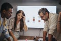 Multicultural business team discussing architectural blueprints in a collaborative office meeting. Royalty Free Stock Photo