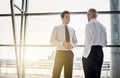 Collaboration, window and flare with business men in discussion while standing in their corporate office. Meeting Royalty Free Stock Photo