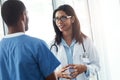 Collaborations that save lives. two young doctors having a discussion in a modern hospital. Royalty Free Stock Photo