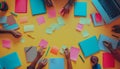 top view of a creative teamwork brainstorming session with colorful sticky notes notebooks and laptop on yellow table Royalty Free Stock Photo