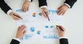 Collaborative business meeting with multiple hands analyzing financial data and charts