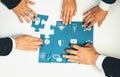 Collaborative Effort in Teamwork with Individuals Assembling Puzzle Pieces Featuring Technology and Innovation Icons on Royalty Free Stock Photo