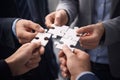Collaborative Teamwork in Action: Individuals Joining Puzzle Pieces to Represent Unified Royalty Free Stock Photo