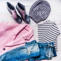 Collage of autumn-winter female clothing set. Pink coat, blue ripped jeans, sriped blouse, knitted hat and black leather boots ove