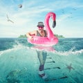 Cheerful man in a striped suit swim in flamingo rubber ring against the background of a summer beach .Collage.