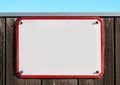 enamel, metal or pottery sign on a rustic wooden wall. red frame, under a bright turquoise sky. Royalty Free Stock Photo