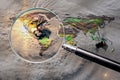 Collage with magnifying glass searching at the earth map with huge hurricane Royalty Free Stock Photo