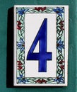 number four ceramic sign made of enamel or clay on a turquoise wooden wall, 4 with flowers Royalty Free Stock Photo